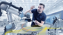 Eine Produktionsmitarbeiterin arbeitet Hand-in-Hand mit einem Roboter.